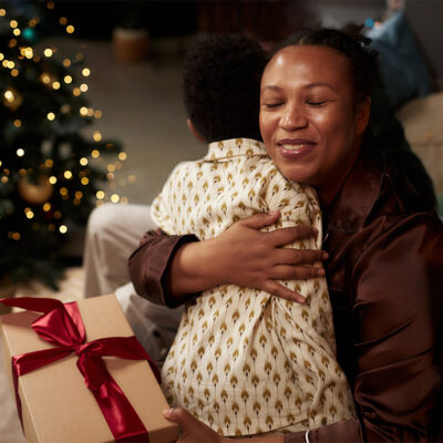 Woman holding her child in front of a Christmas tree
