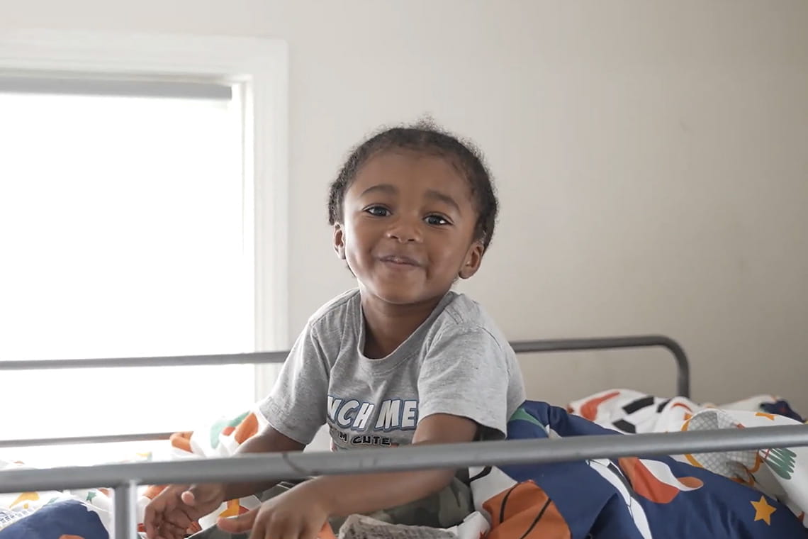 Image of child on bed furnished by the Furniture Bank of Metro Detroit